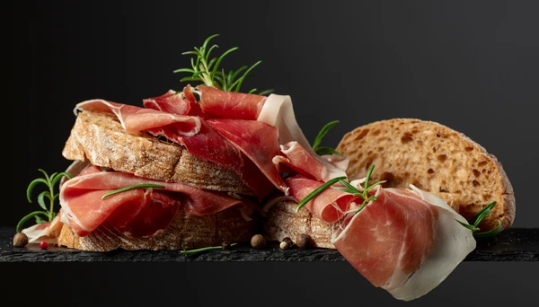 Intérieur cuisine professionnelle, charcuterie artisanale avec tranches de viande séchée fumée disposées sur planche bois rustique