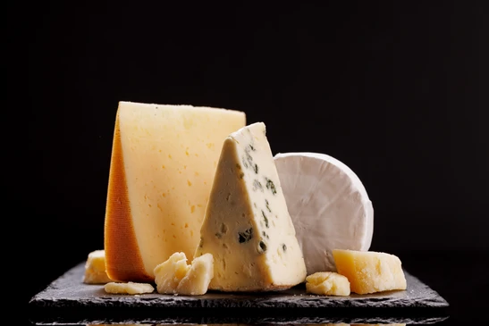 assiette de fromage: Emmental, fromage Camembert, fromage bleu, bâtonnets de pain, noix, noisettes, miel, raisins sur table en bois