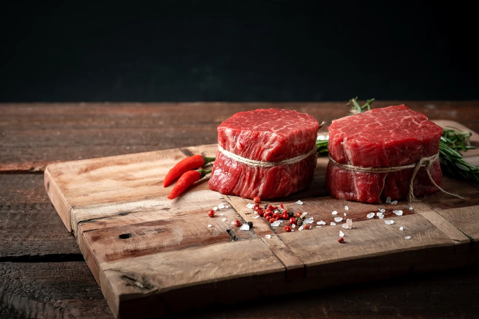 Scène culinaire dynamique avec viande rouge crue en mouvement au-dessus d'une poêle noire