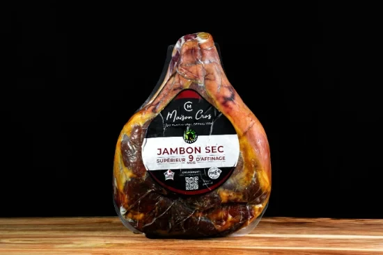 Saucisses grillées artisanales disposées sur planche à découper en bois, accompagnées de moutarde en pot céramique et herbes fraîches, présentation gastronomique professionnelle