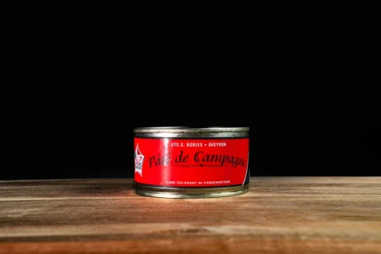 Saucisses grillées artisanales disposées sur planche à découper en bois, accompagnées de moutarde en pot céramique et herbes fraîches, présentation gastronomique professionnelle