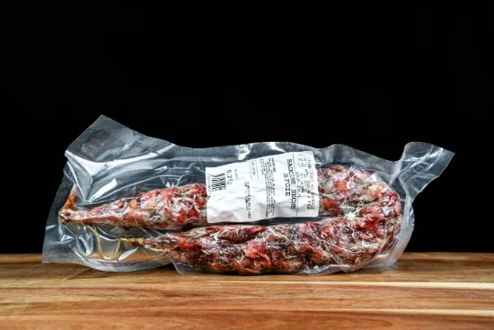 Saucisses grillées artisanales disposées sur planche à découper en bois, accompagnées de moutarde en pot céramique et herbes fraîches, présentation gastronomique professionnelle