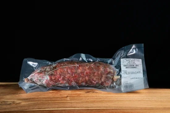Saucisses grillées artisanales disposées sur planche à découper en bois, accompagnées de moutarde en pot céramique et herbes fraîches, présentation gastronomique professionnelle