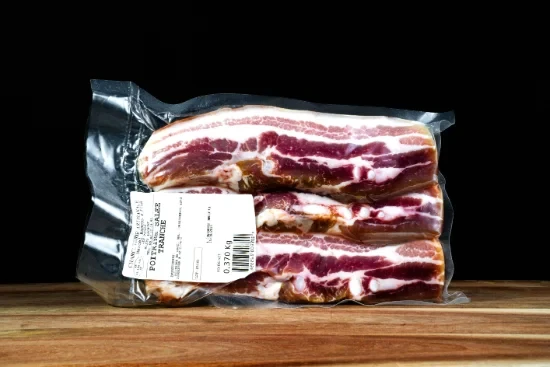Saucisses grillées artisanales disposées sur planche à découper en bois, accompagnées de moutarde en pot céramique et herbes fraîches, présentation gastronomique professionnelle