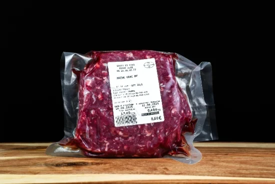 Scène conviviale de dégustation gastronomique avec personne tenant un verre de vin rouge au-dessus d'une table garnie de charcuteries, fromages, olives et cornichons disposés sur planches de bois