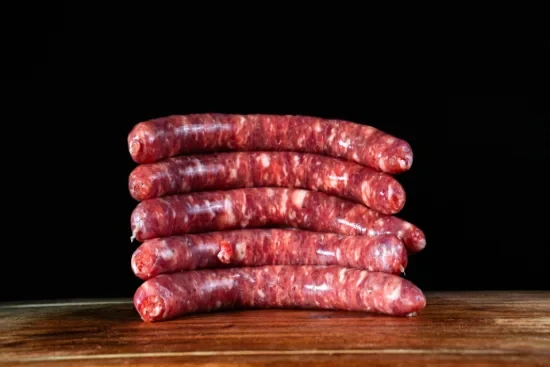 Scène conviviale de dégustation gastronomique avec personne tenant un verre de vin rouge au-dessus d'une table garnie de charcuteries, fromages, olives et cornichons disposés sur planches de bois